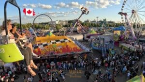 Colorful amusement park rides at a lively fair in Canada, full of visitors enjoying the fun and vibrant atmosphere.
